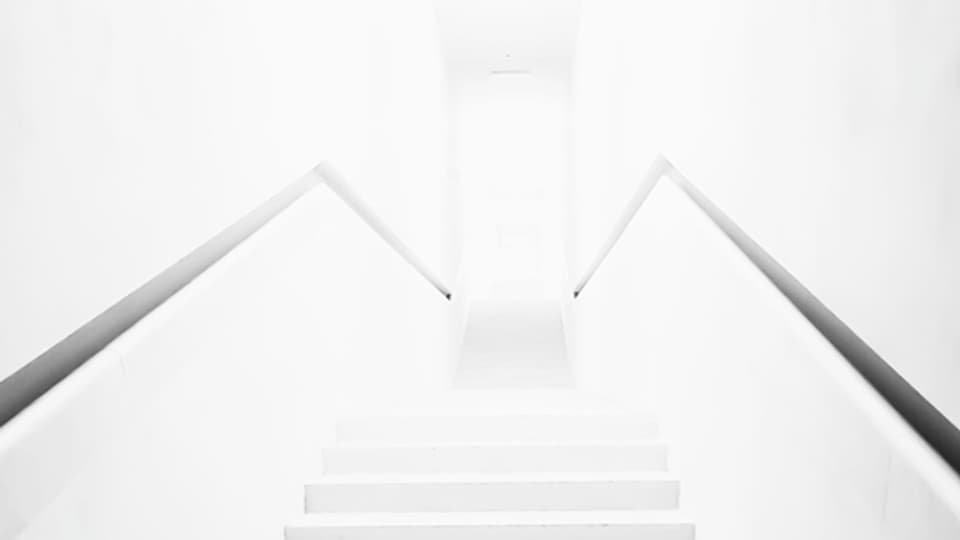 Weisse Treppe überstrahlt führt zu einer weissen Tür.