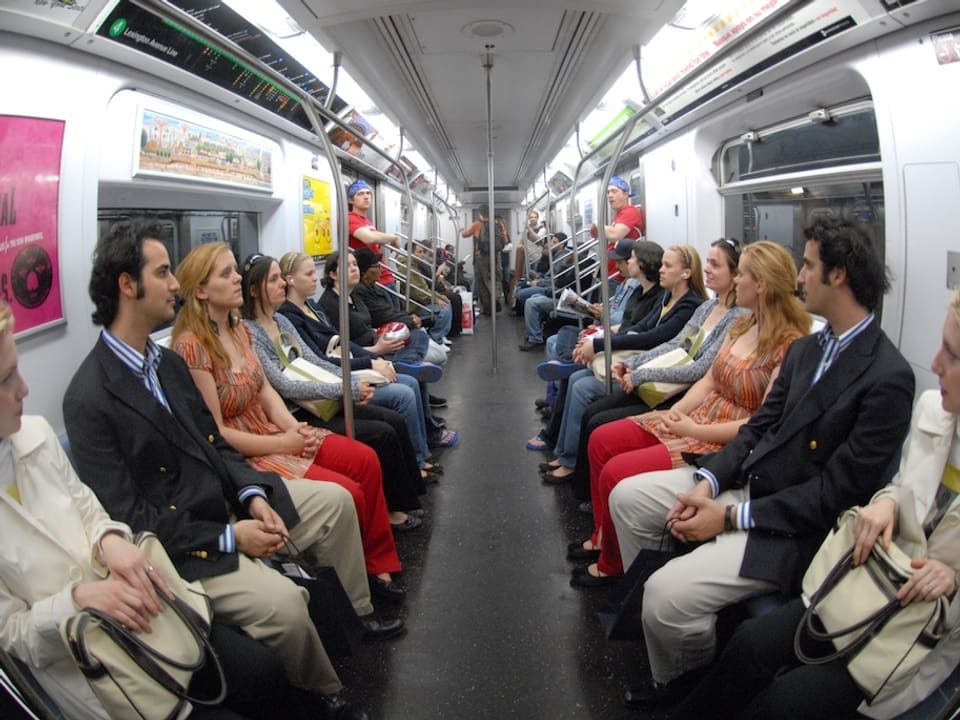 U-Bahn besetzt mit sich gegenübersitzenden eineiigen Zwillingen