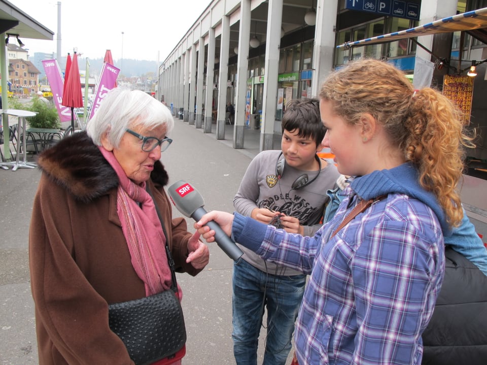 Kinder interviewen eine ältere Dame. 