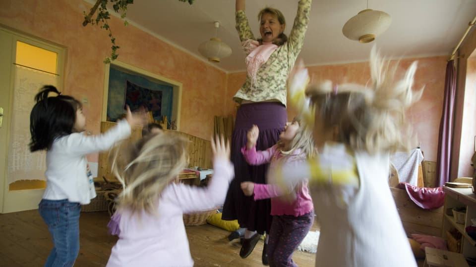 Kinder und Kindergärtnerin springen in die Luft.