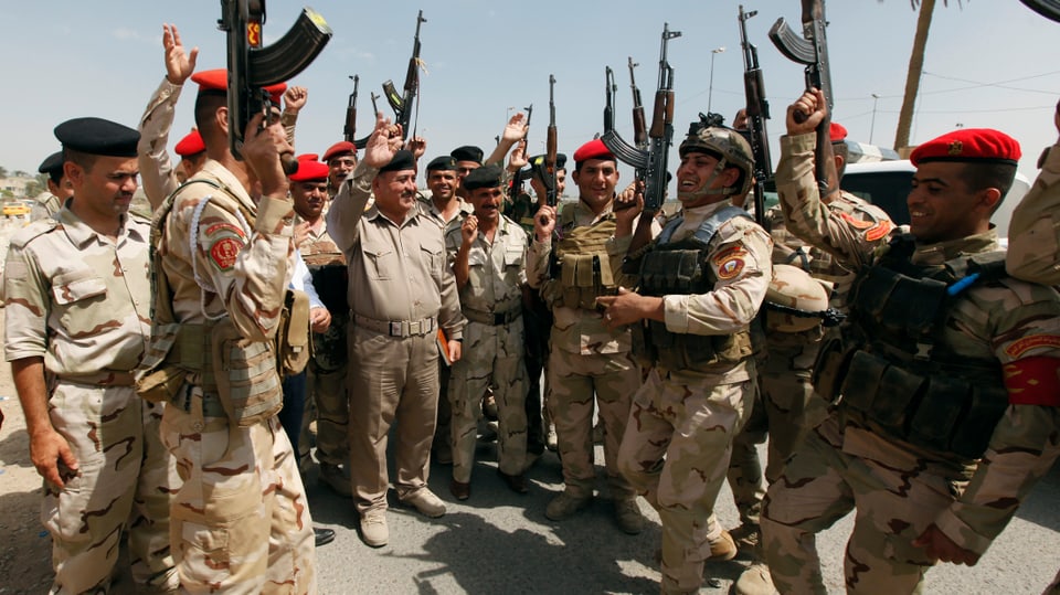 Irakische Soldaten stehen nebeneinander und halten Gewehre in die Luft