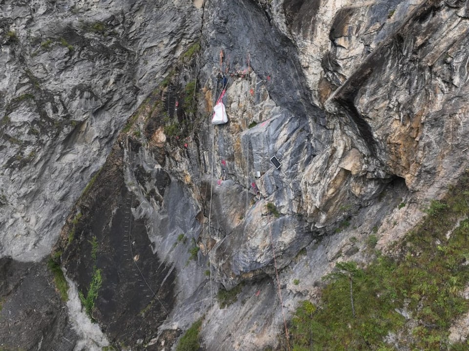 Alpinistas em rocha íngreme com cordas e equipamentos.