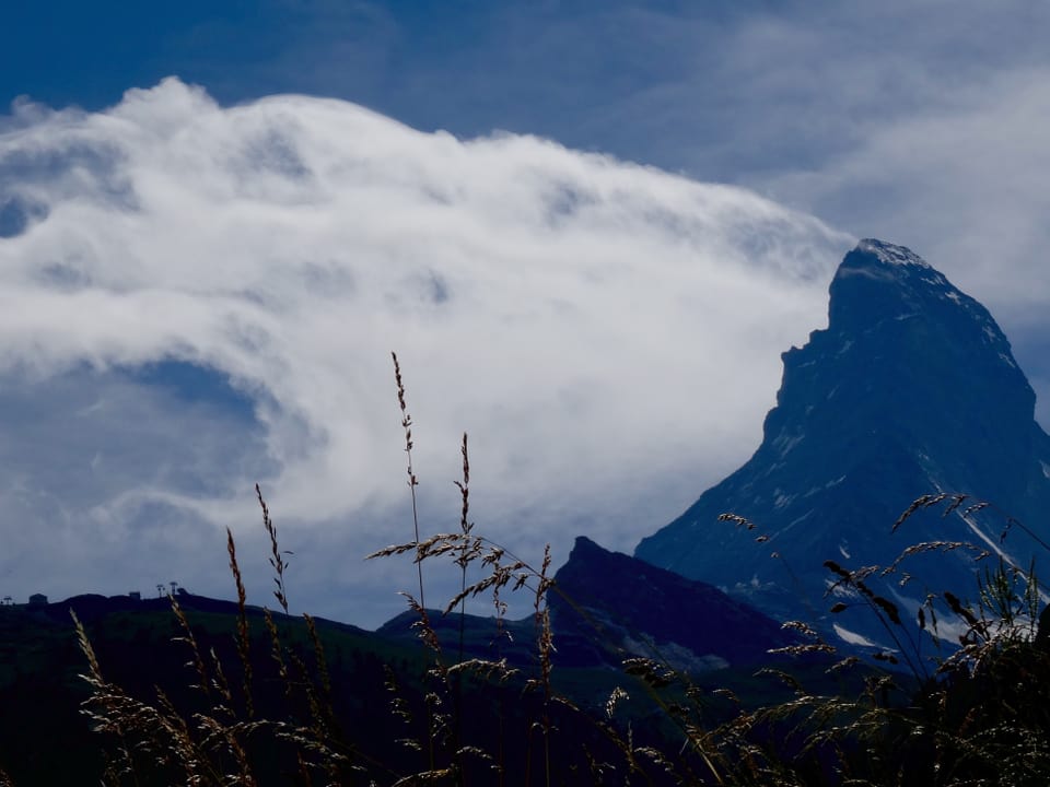 Rechts im Bild das Matterhorn. Links davon eine Wolkenfahne die sich zum linken Bildrand langsam ausdünnt.