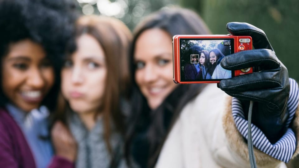 Drei Frauen unterschiedlicher Hautfarben machen ein Selfie mit einer Digitalkamera.