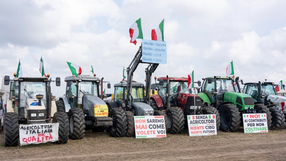 Traktore stehen nebeneinander, dabei sind Italienflaggen und Plakate.