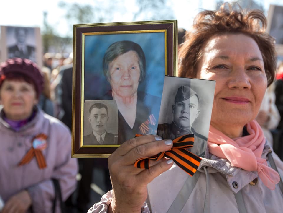 Eine Frau hält fotografische Porträts in ihrer rechten Hand.