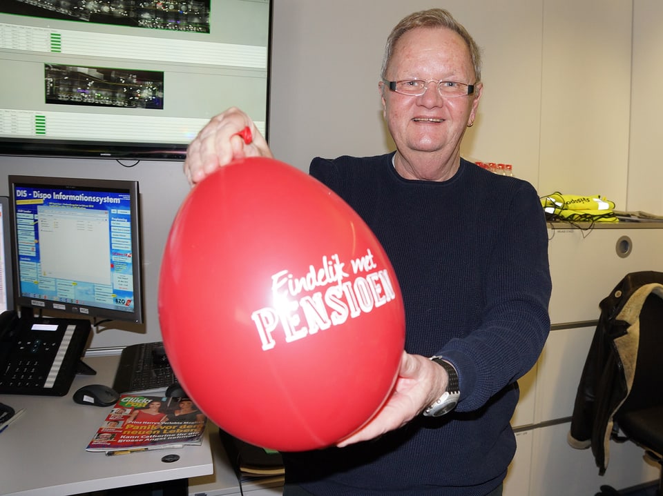 Ein Mann hält einen grossen roten Ballon in der Hand.