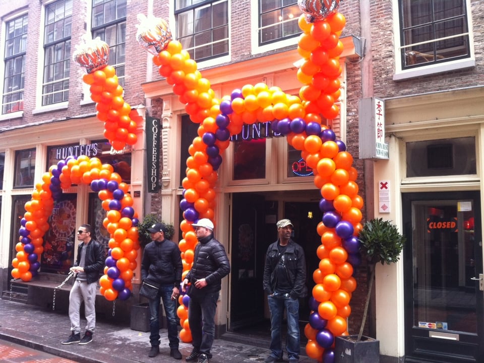 Luftballons in Orange rahmen die Tür eines Coffeeshops in Amsterdam