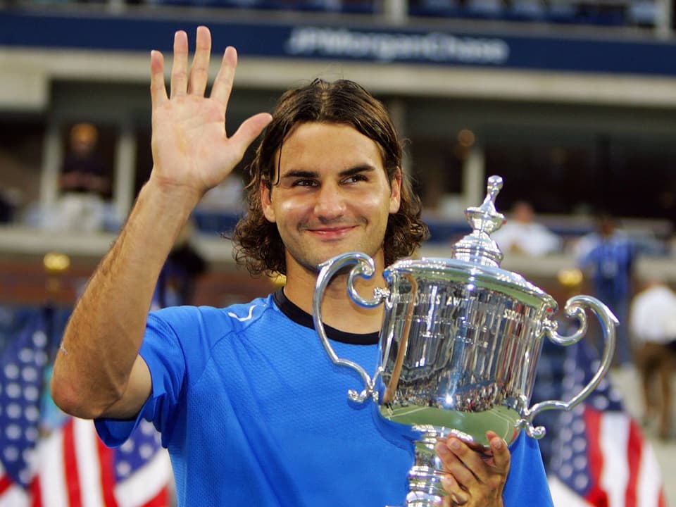 Roger Federer hält eine Trophäe hoch.