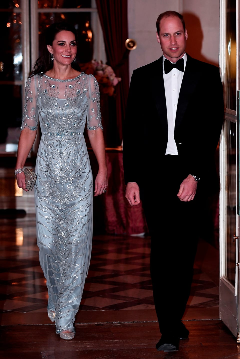 Kate in einem hellblau-silbernen Glitzerkleid und William im Anzug mit Fliege.