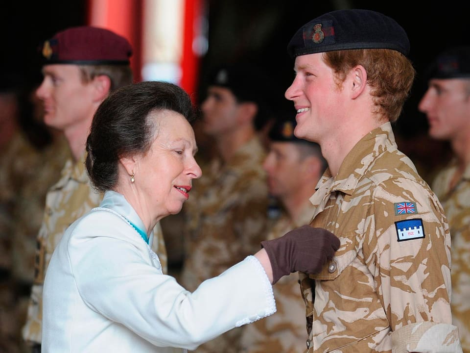 Prinzessin Anne überreicht Prinz Harry ein Abzeichen.