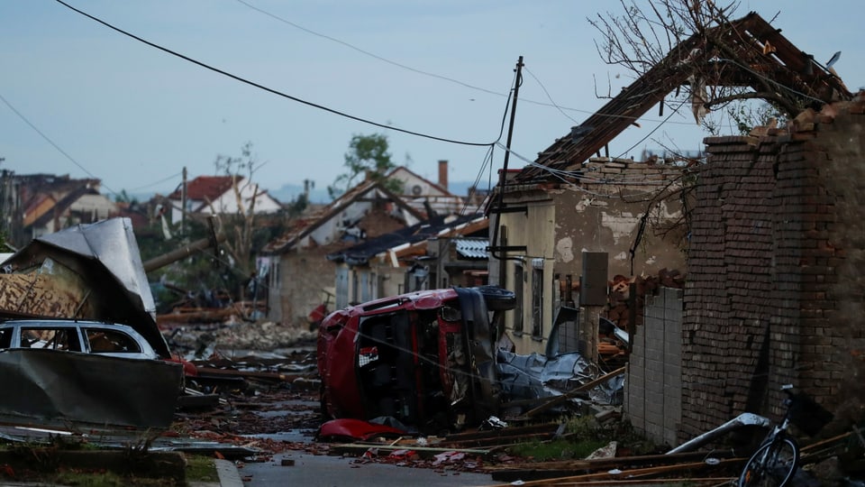 Tornado hinterlässt Trümmer von Häusern und umgekippte Autos.