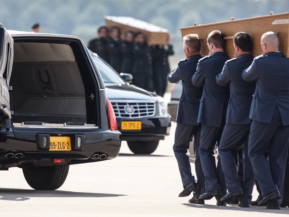 Niederländische Ehrengarden nehmen die Särge der Absturzopfer am Flughafen Eindhoven in Empfang und tragen sie in Leichenwagen.