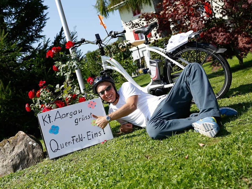 Reto Scherrer posiert neben einem Schild auf dem steht: Kt. Aargau grüsst Querfeldeins.
