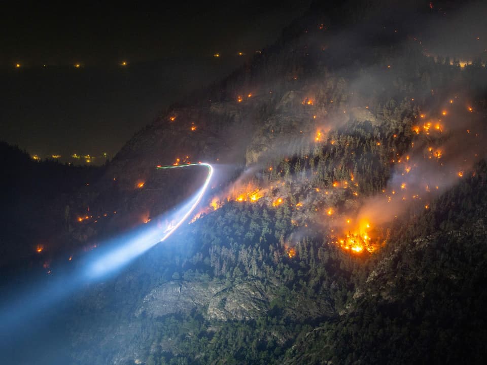 Blick auf erhellten Hang mit lodernenden Flammen bei Nacht