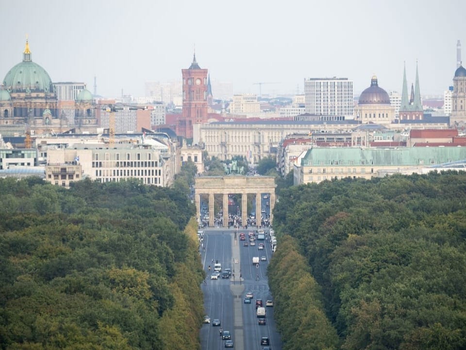 Blick über die Strasse des 17. Juni zur Berliner Siegessäule mit umgebenden Gebäuden und Vegetation.