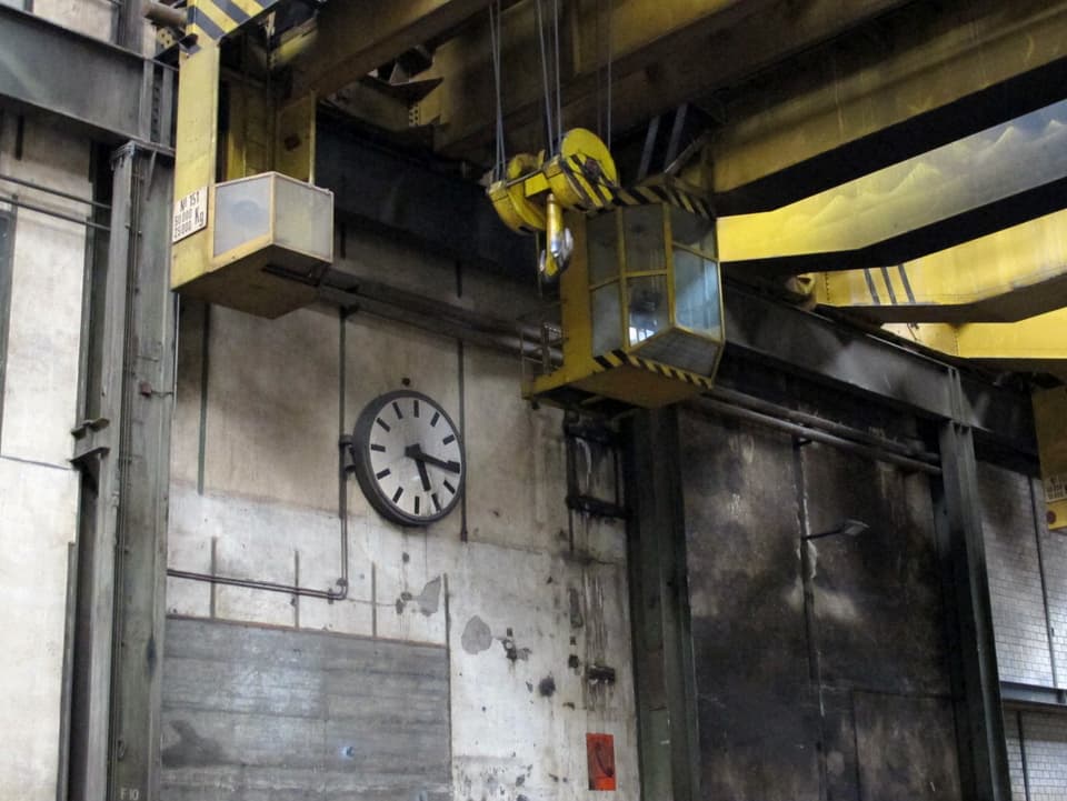Werkuhr und Kran in der Fabrikhalle.