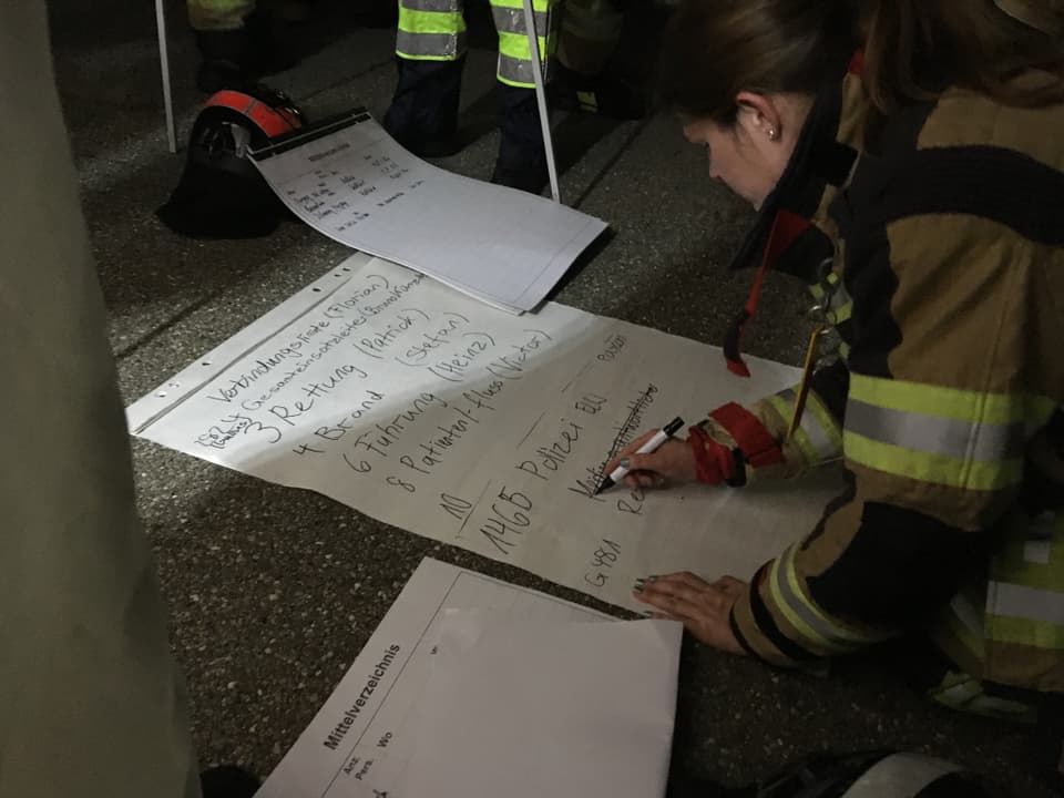 Feuerwehrfrau macht Notizen auf Plakat