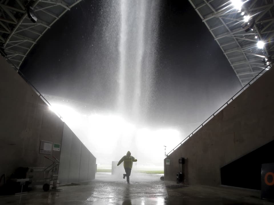 Eine Person flüchtet vor dem Regen in einem Stadion. 