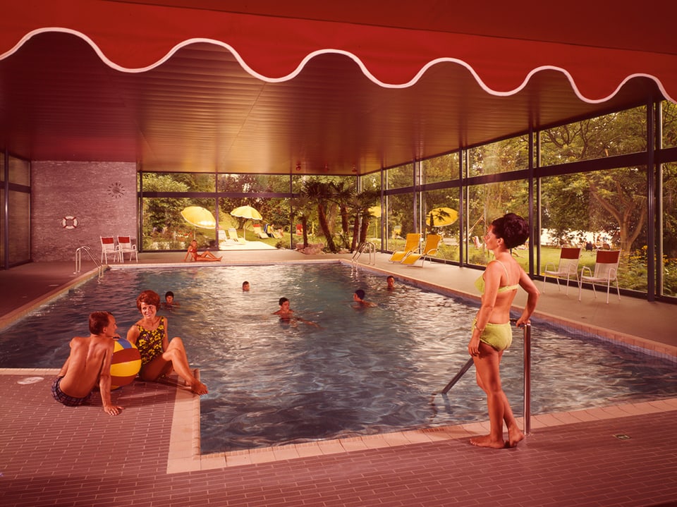 Ein Indoor-Swimmingpool mit Schwimmenden und einer Frau, die am Rand steht.