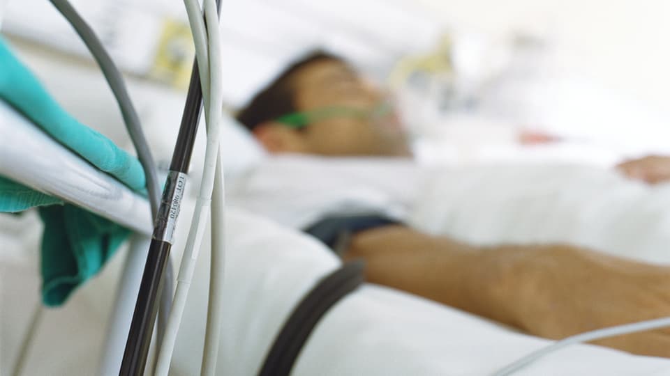 Ein Mann liegt in  verkabelt in einem Spitalbett.