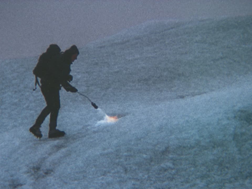Aktionskünstler mit Bunsenbrenner Spuren in Gletscher brennend.