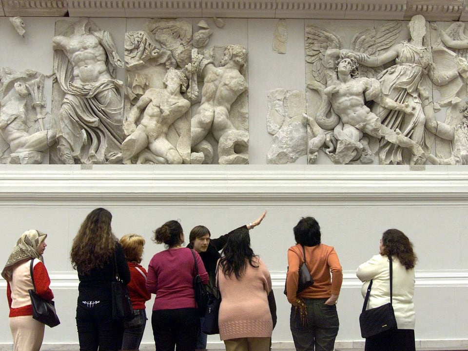 Besuchergruppe vor einem antiken Relief