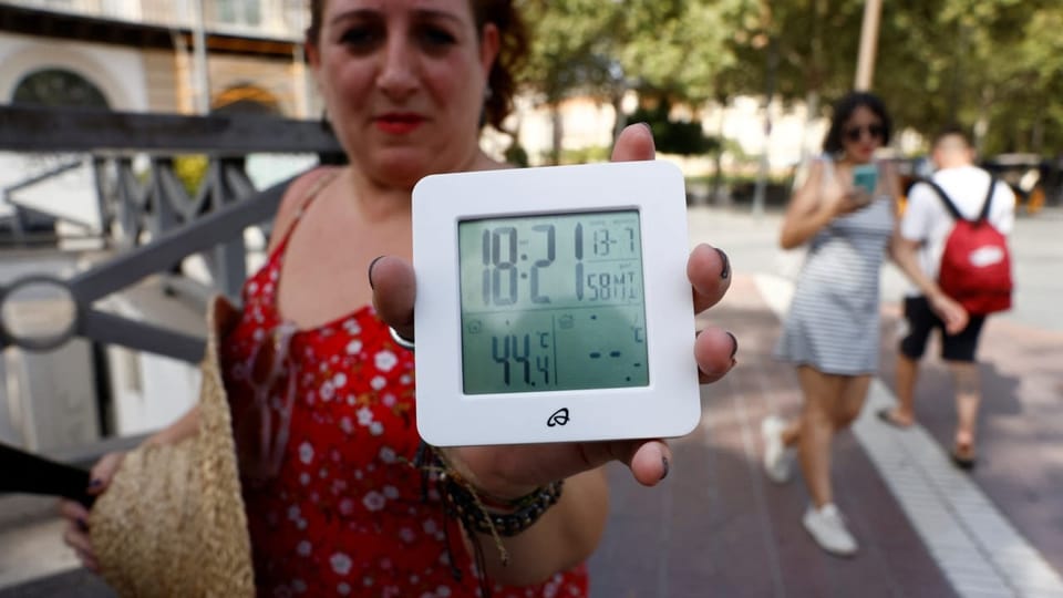Frau zeigt Thermometer in die Kamera