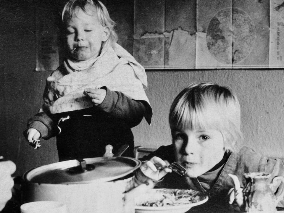 Ein Schwarz-weiss-Foto zeigt zwei Kinder beim Essen.