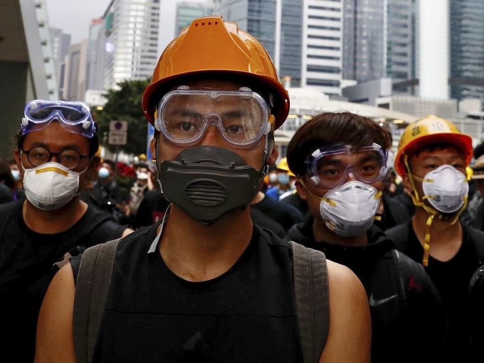 Männer mit Taucherbrillen und Gesichtsmasken gehen durch die Strassen von Hongkong.