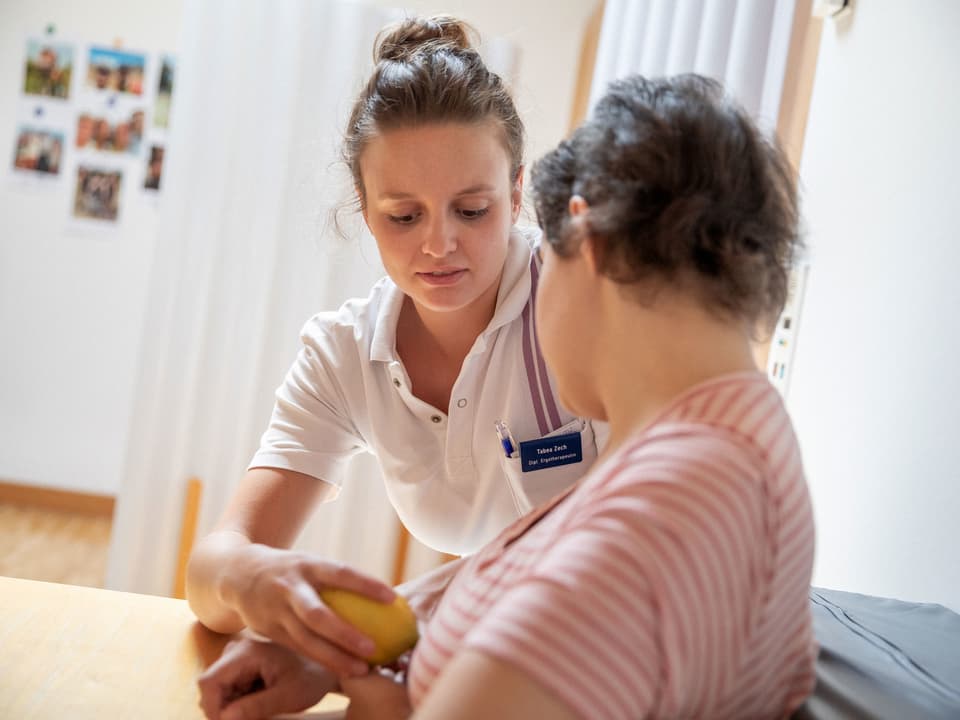 Betreuerin gibt Patientin eine Zitrone in die Hand