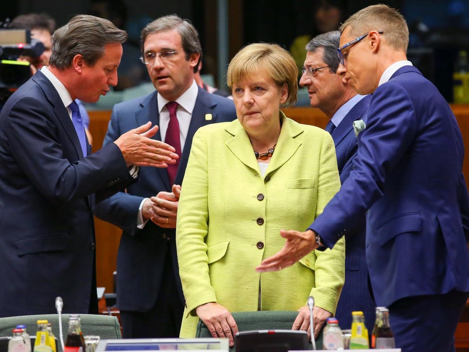 Angela Merkel umgeben von Männern. Sie trägt einen gelben Blazer.