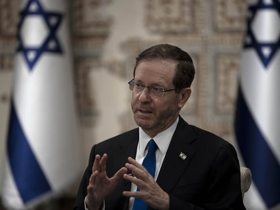 Isaac Herzog steht vor zwei Israelfahnen