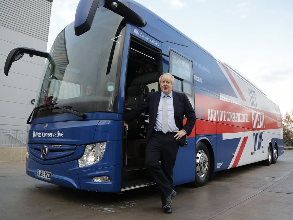 Johnson lehnt an einem Bus mit der Aufschrift "Get Brexit Done".