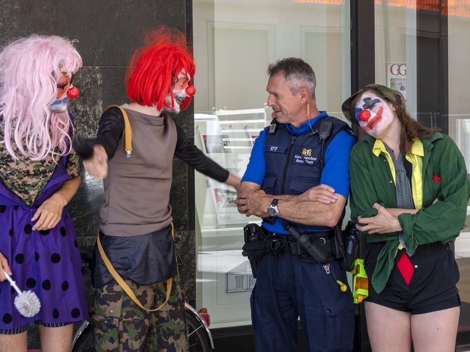Demonstranten in Clown-Kostümen und ein Polizist