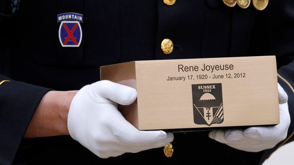 Soldat hält mit weissen Handschuhen Urne von Rene Joyeuse.