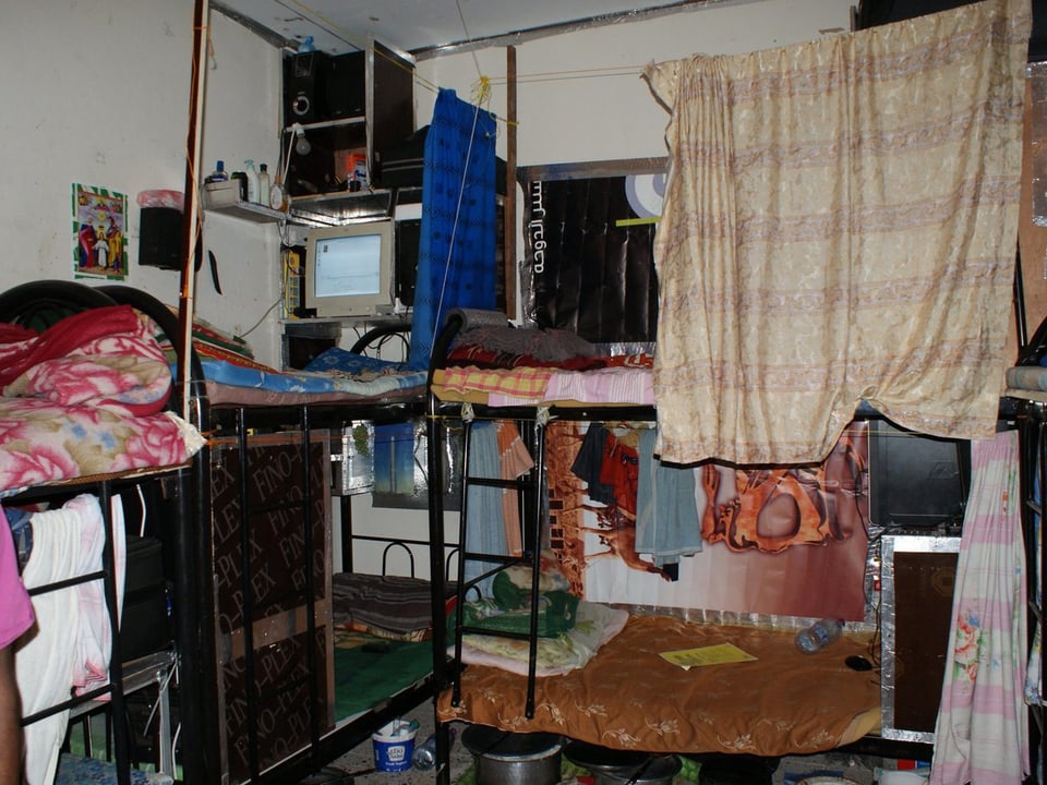 Mehrere Etagenbetten, teilweise verhängt mit Tüchern als eine Art Vorhänge.