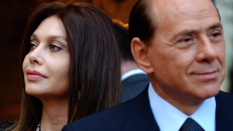 Lario, links im Bild, schaut von Berlusconi weg.