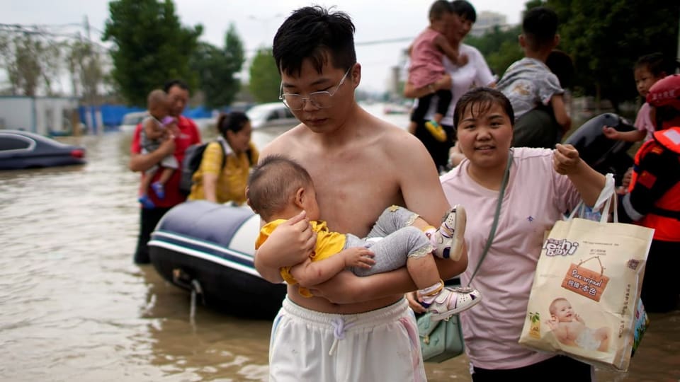Mann mit Baby bei Überschwemmung