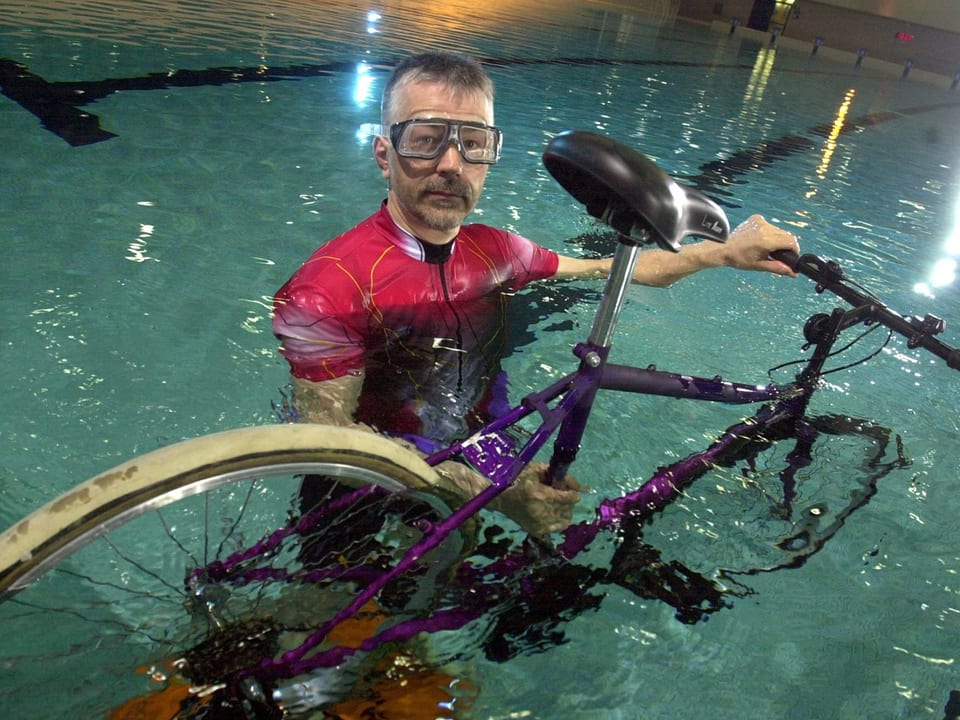 Bernhard Wagner posiert mit Taucherbrille und Fahrrad im Schwimmbecken.