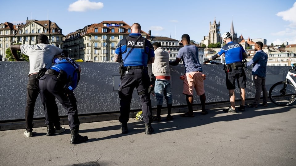 Eine Gruppe weisser Polizisten kontrolliert eine Gruppe schwarzer Männer