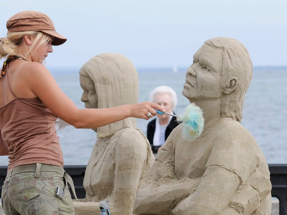 Künstlerin arbeitet an einer Sandfigur.