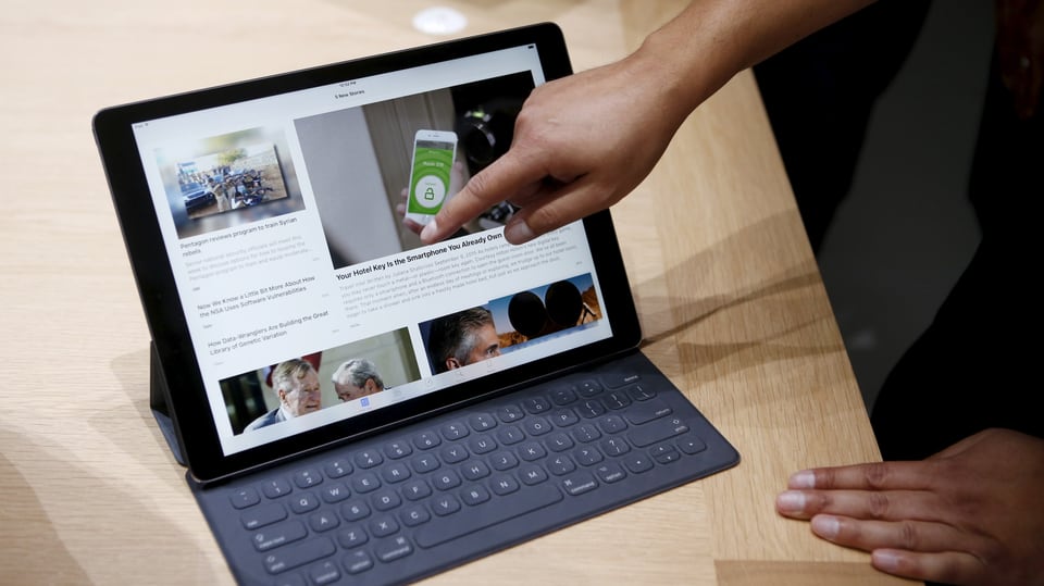 Eine Hand zeigt auf das neue iPad Pro, das in seiner Tastatur-Hülle steckt.