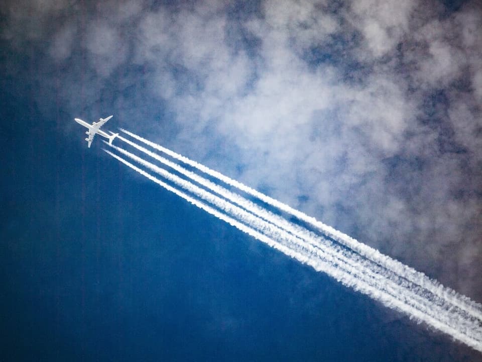 Flugzeug am Himmel mit Kondensstreifen.