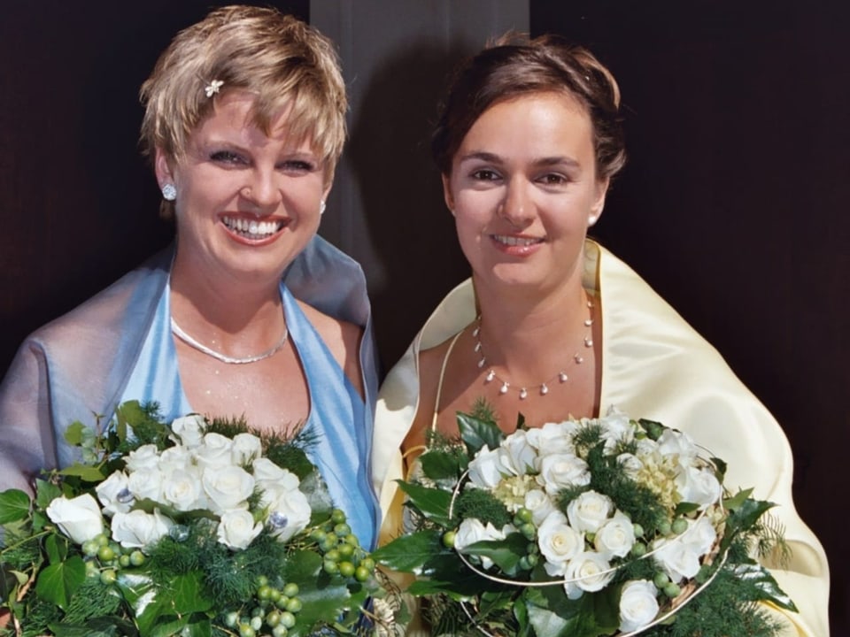 Zwei Frauen im Hochzeitskleid mit Blumenstrauss in der Hand