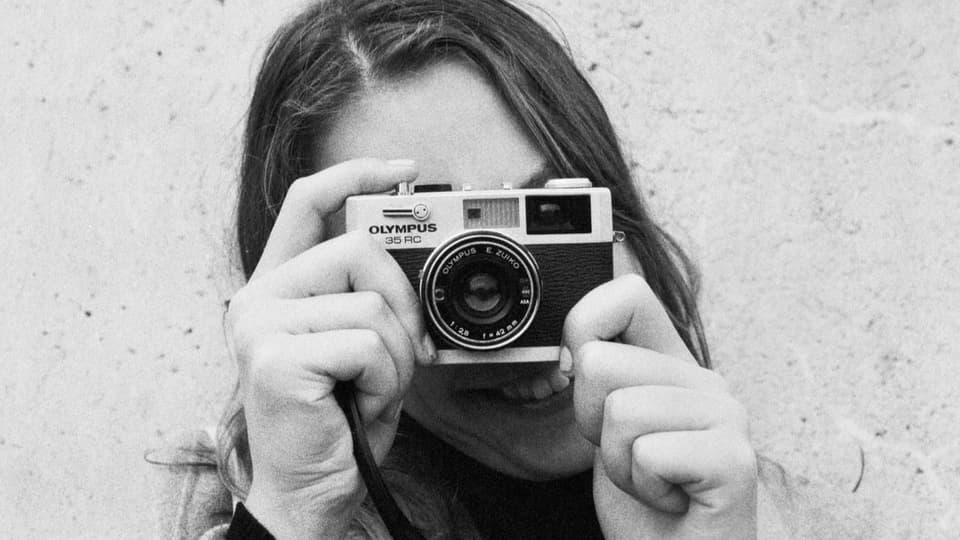 Portrait einer jungen Frau mit einer Analogkamera (Schwarz-Weiss-Bild)