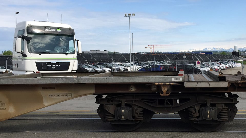 Ein Lastwagen mit Railcare-Schriftzug steht hinter einem leeren Güterwagen der Eisenbahn