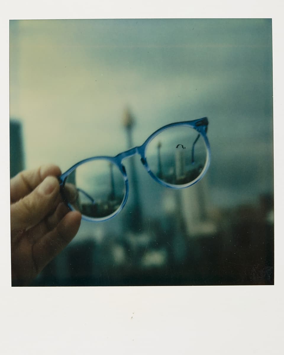 Durch die Brillengläser sieht man die verschwommene Skyline einer Stadt.