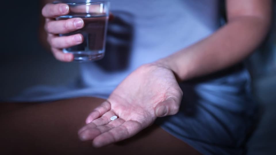 Melatonin: Das Hormon der Dunkelheit Eine Person hält eine Tablette in der Hand.