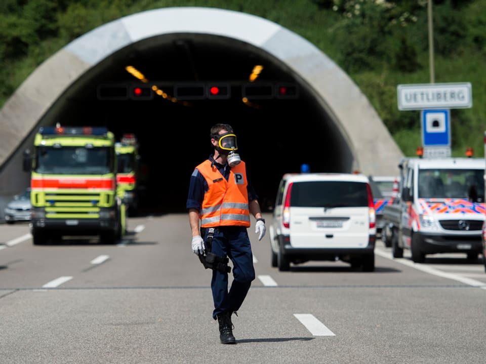 Ein Polizist mit Gasmaske vor dem Tunnelportal, im Hintergrund Einsatzfahrzeuge.